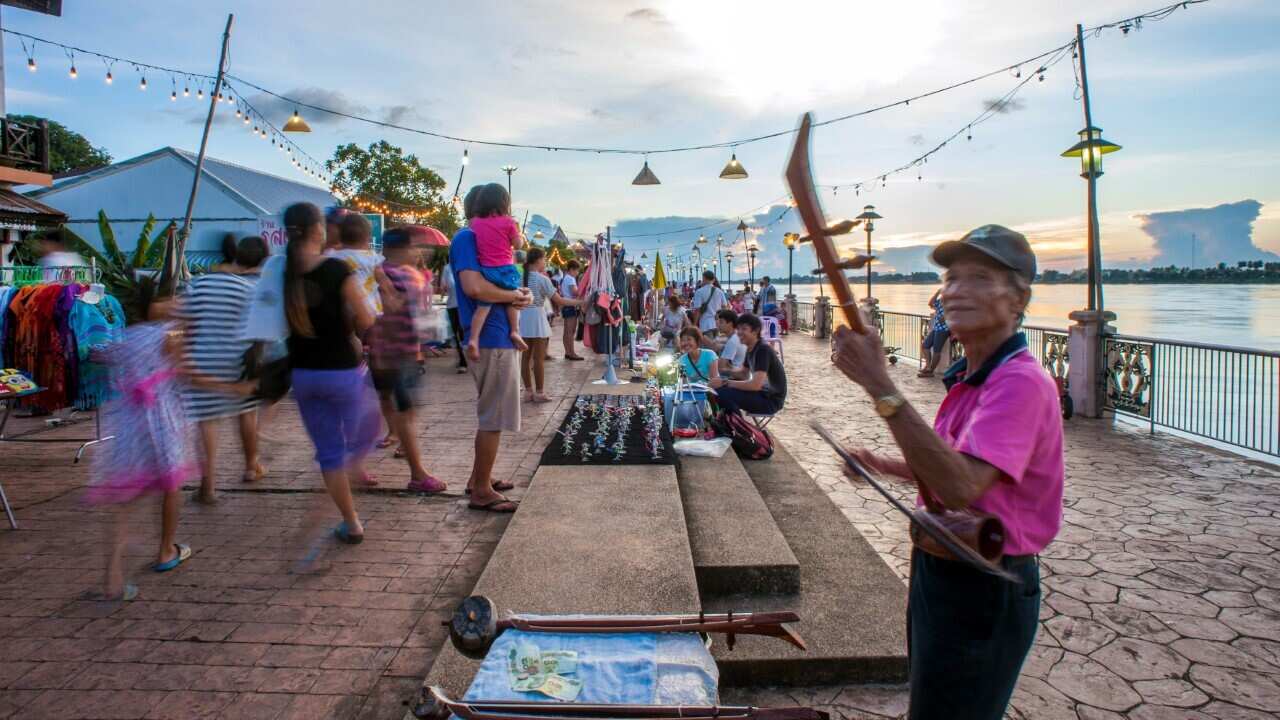 A musician busks for change at a night market set up long the Mekong River Nong Khai (Leisa Tyler - LightRocket via Getty Images)