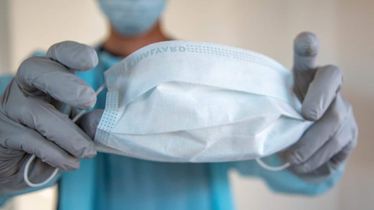 A health care worker holds a face mask.