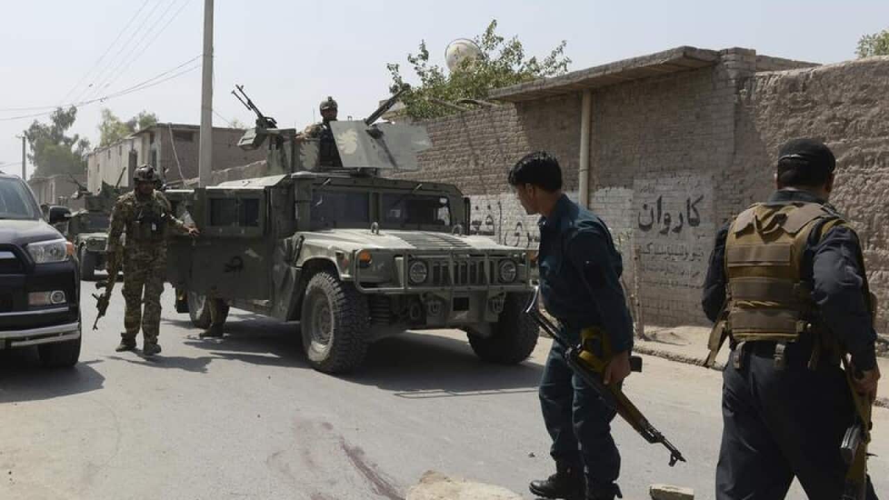 Afghan security forces inspect at the site of a suicide bombing.