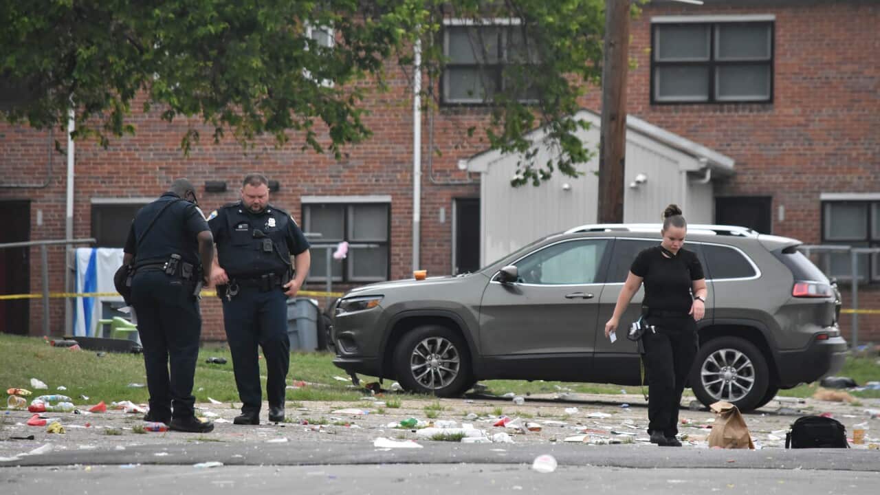 Two men and a woman in police uniform on the scene of a mass shooting incident.