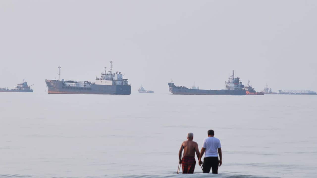 Two men wade in the waters of the Strait of Hormuz with vessels anchored in the background, off Bandar Abbas, Iran (Razieh Poudat-ISNA via AP).jpg
