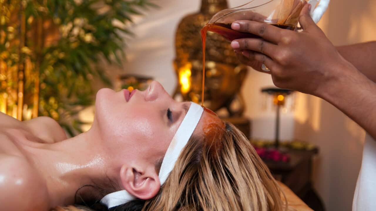 A woman has a soothing Ayurveda massage to her forehead