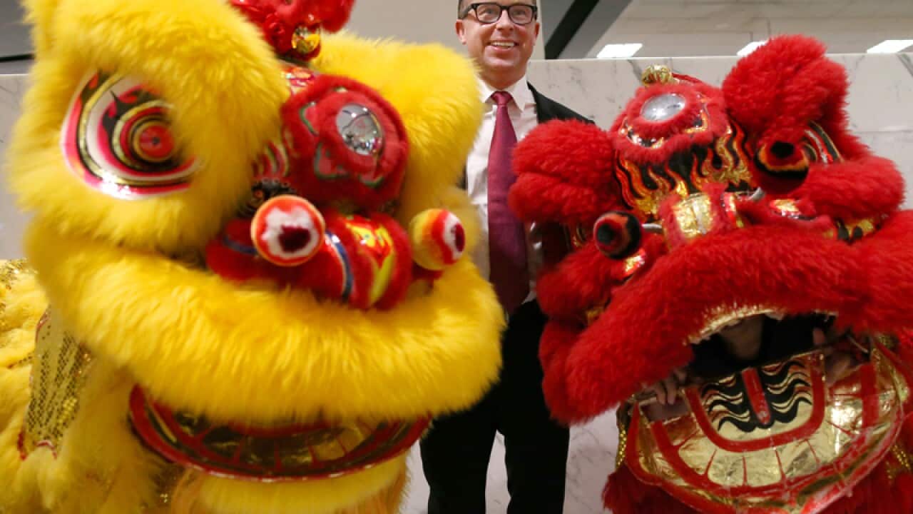 Qantas CEO Alan Joyce laughs as he poses with two Chinese Lion dancers