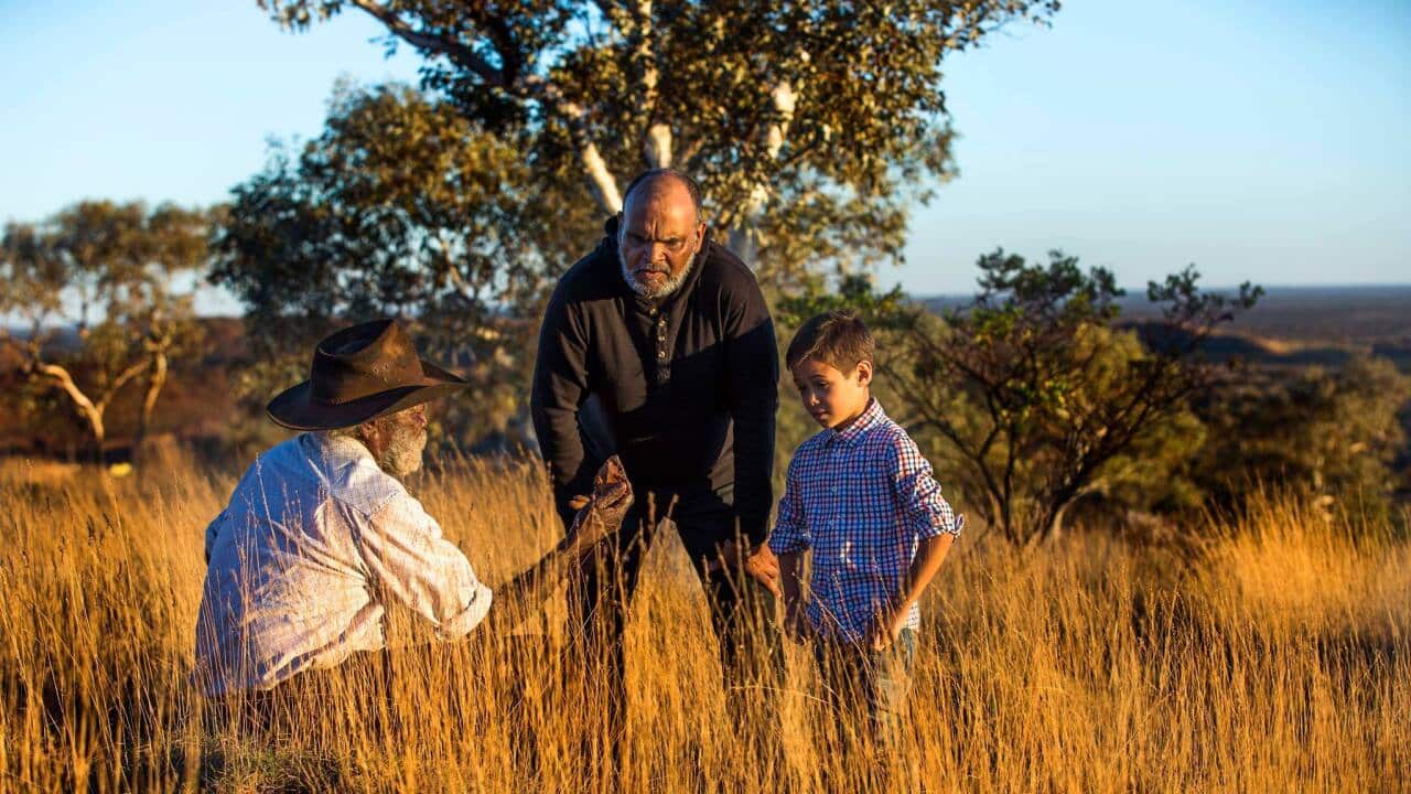 Elder showing child artefact in long grass