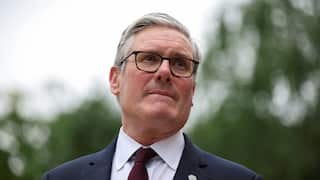 British Prime Minister Keir Starmer looking away from camera outdoors, wearing glasses, a dark suit and burgundy tie, following the announcement of his resignation.