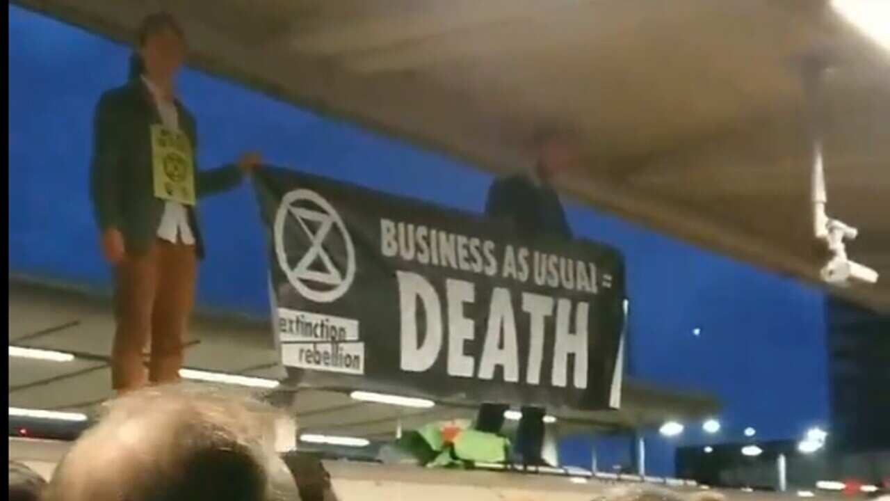Extinction Rebellion protesters on the roof of an underground train surrounded by angry commuters at Canning Town station in east London.