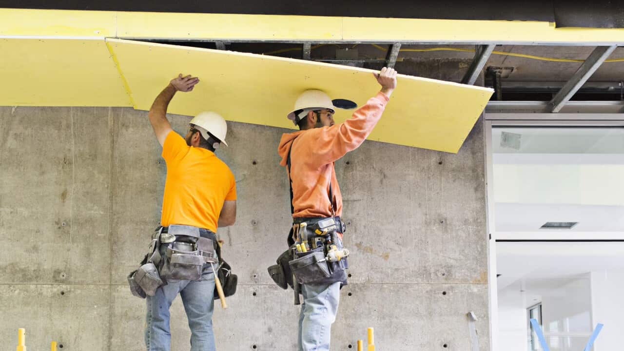 Construction workers applying insulation
