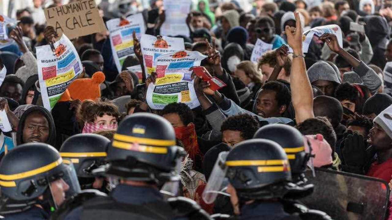 Participants face the police during a march organized by human rights activists in support of migrants and refugees in the so-called 'Jungle' camp.