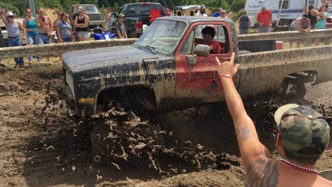 Spectators cheer as a pickup truck splashes through mud at an event formerly called the Redneck Olympics