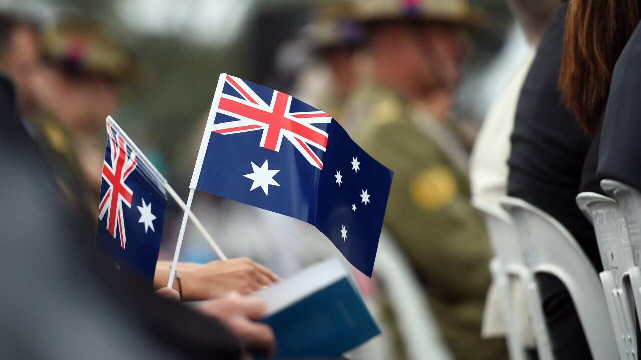 Memmbers of the public hold flags at an Australia Day Citizenship Ceremony and Flag Raising event in Canberra