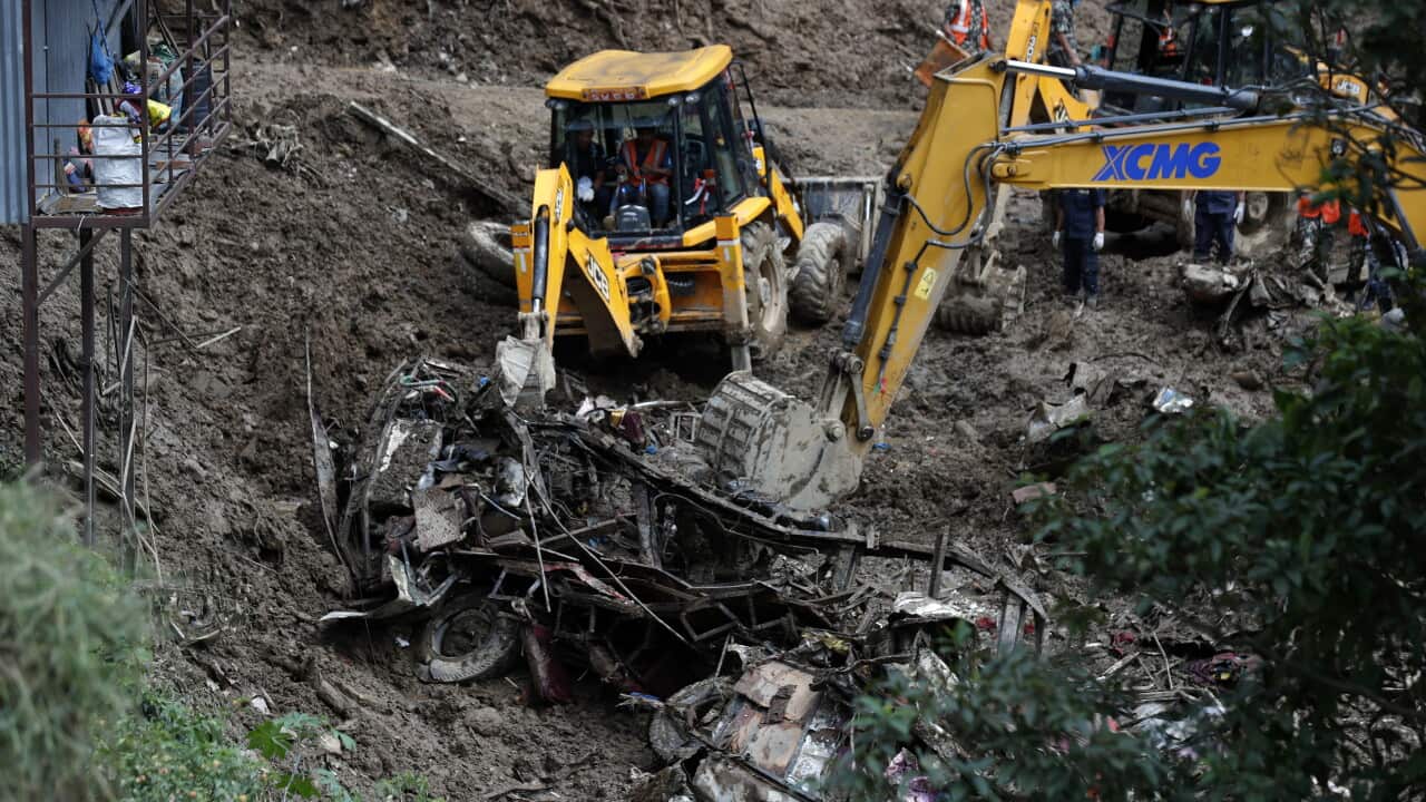 Digger removing car debris from landslide.