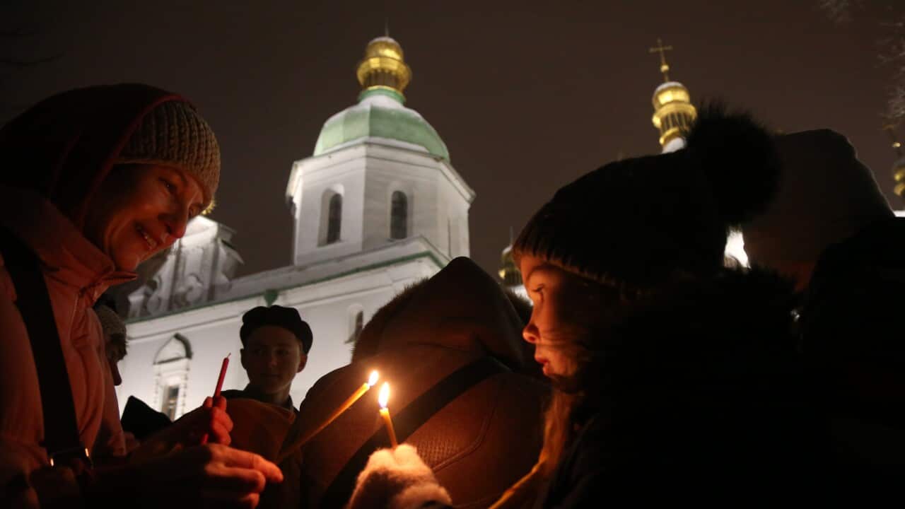In the scene, people are passing a holy light, with a white church visible in the background.