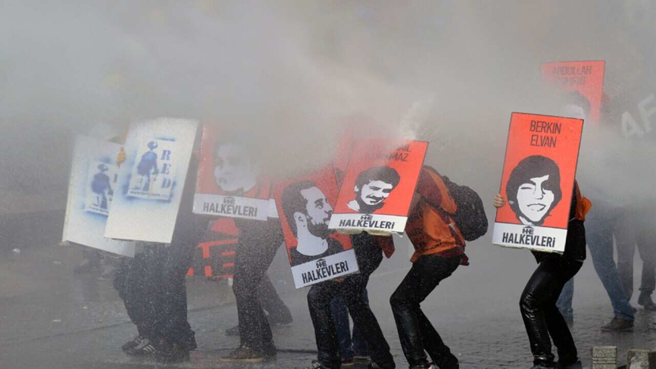 Protesters hold posters as riot police use water cannons