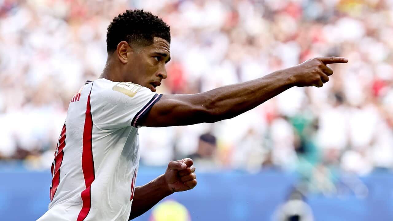 Jude Bellingham, English footballer dressed in red and white, points as he celebrates a goal during the Norway v England quarter final match at the 2026 World Cup.