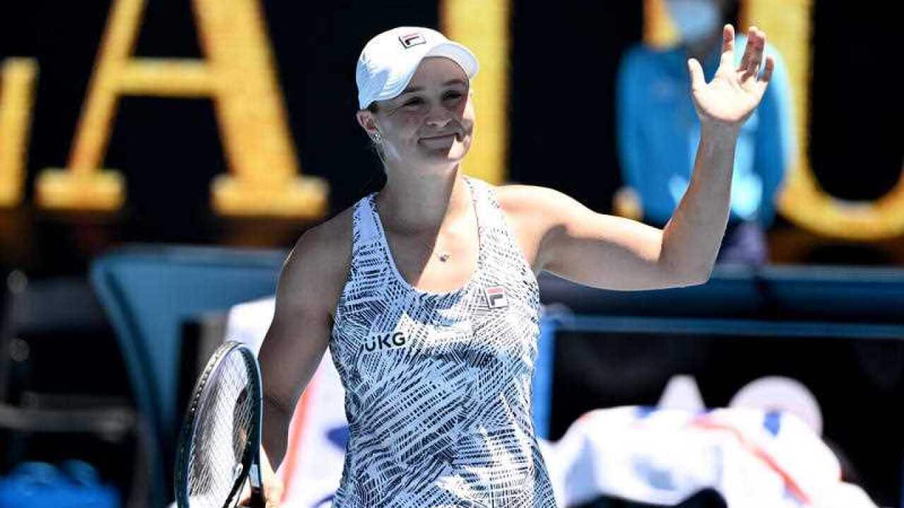 Ash Barty smiles and waves to the crowd at the Australian Open.
