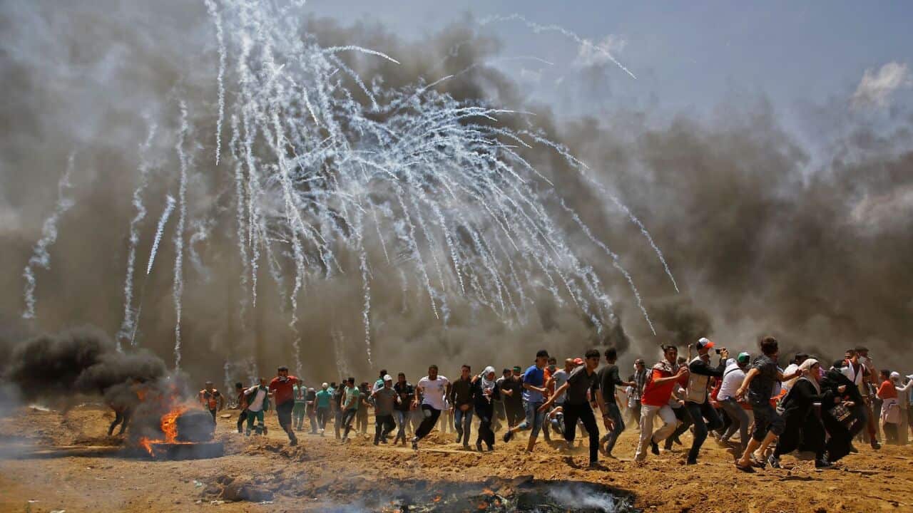 Palestinians run for cover from tear gas during clashes with Israeli security forces on May 14.