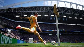 A man in a yellow football uniform kicks the ball out from the corner