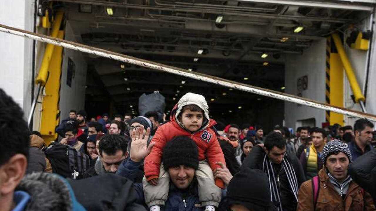 Refugees and migrants disembark from a ferry after their arrival at the port of Piraeus near Athens