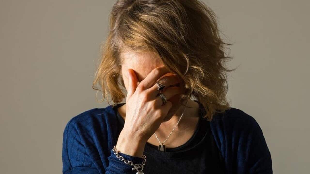 A woman with her head in her hands suffering a migraine.