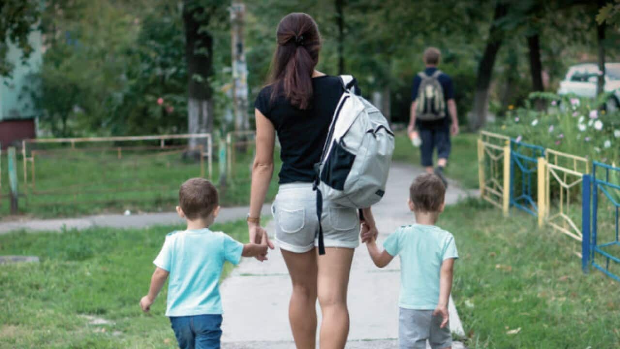 An au pair walks between two children