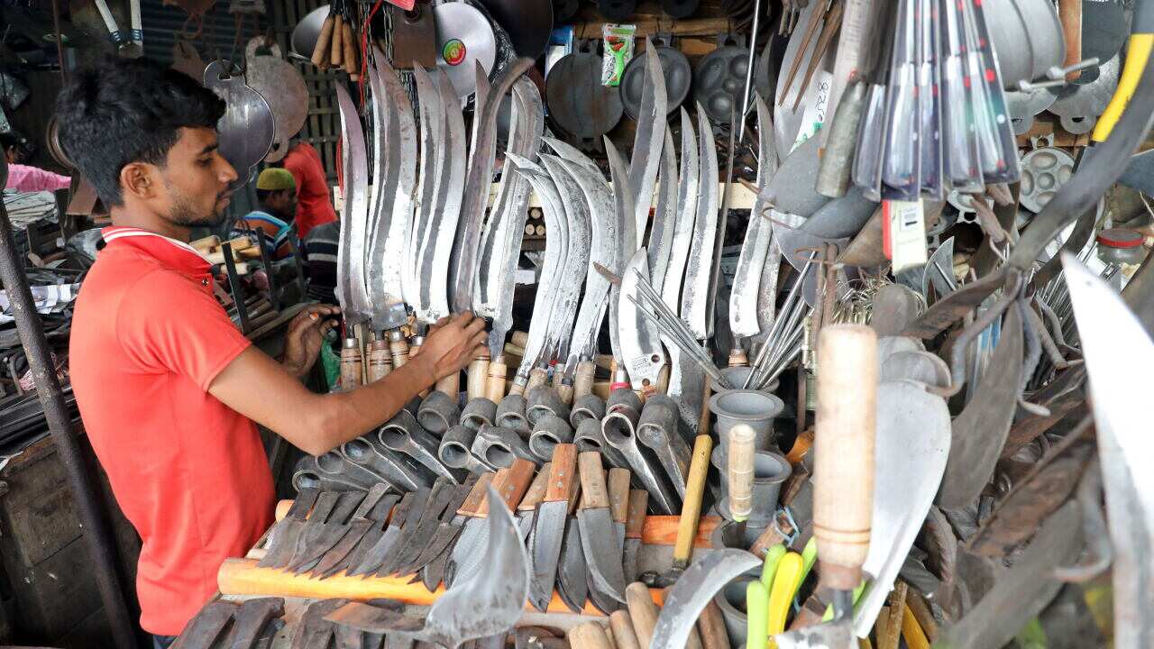 A Bangladeshi Blacksmith makes knives and shopkeeper waits for customer in a knives shop at market in Dhaka, Bangladesh.