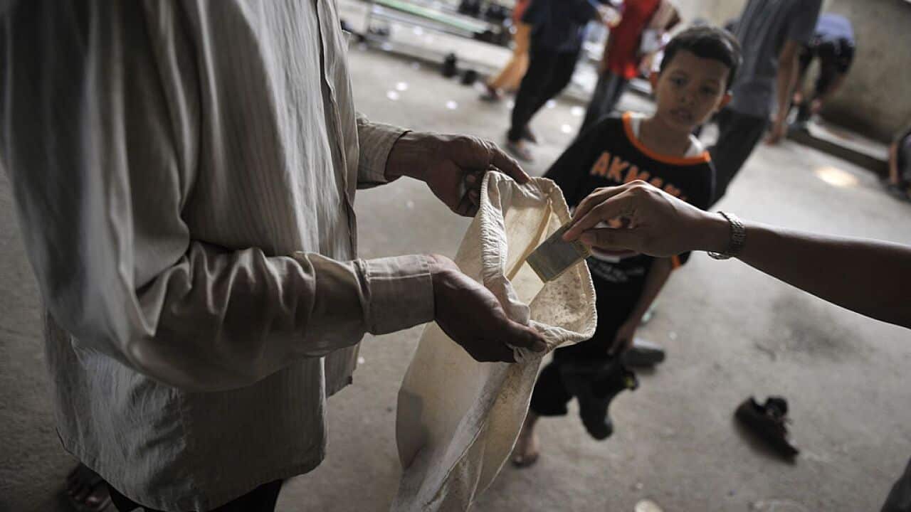 An Indonesian Muslim devotee hands money