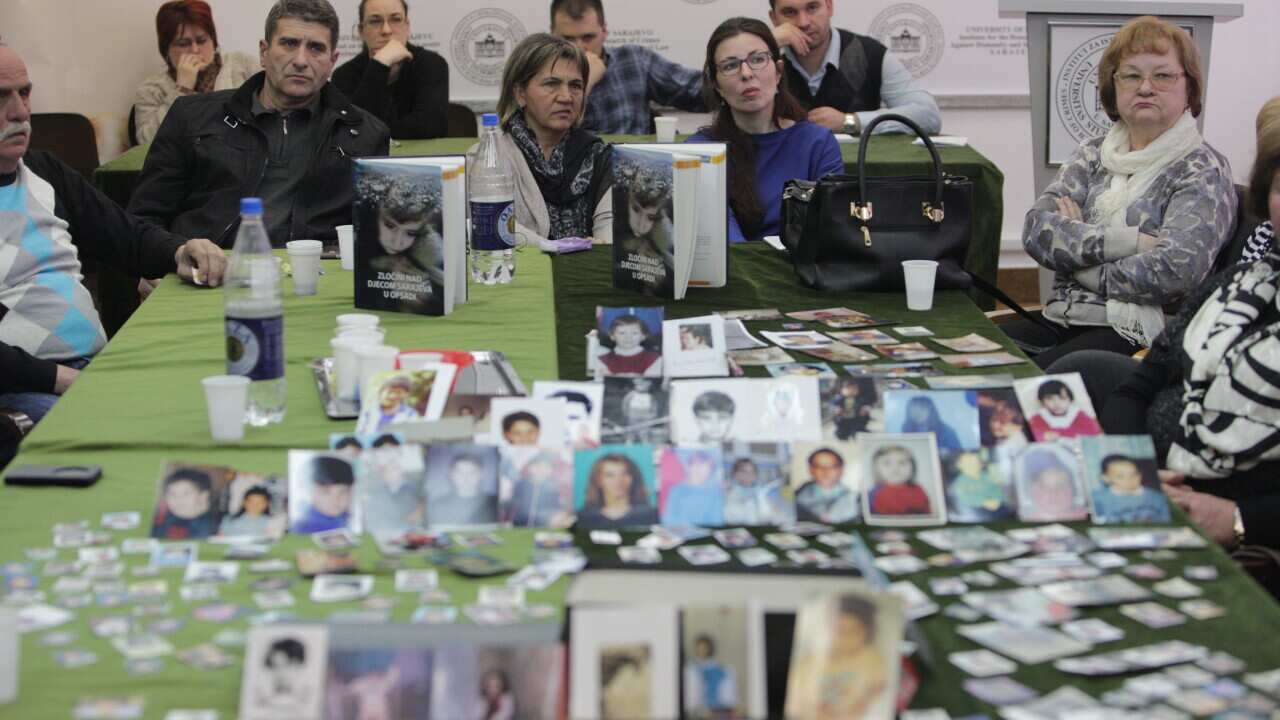 Victims pictures are displayed on a table as people watch the International Criminal Tribunal for Former Yugoslavia court verdict session