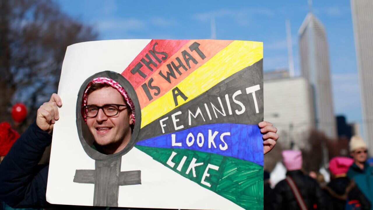 A man holds up a sign as he takes part in the Second Annual Womens March Chicago on January 20, 2018 in Chicago, Illinois. / AFP PHOTO / JIM YOUNG (Photo credit should read JIM YOUNG/AFP/Getty Images)