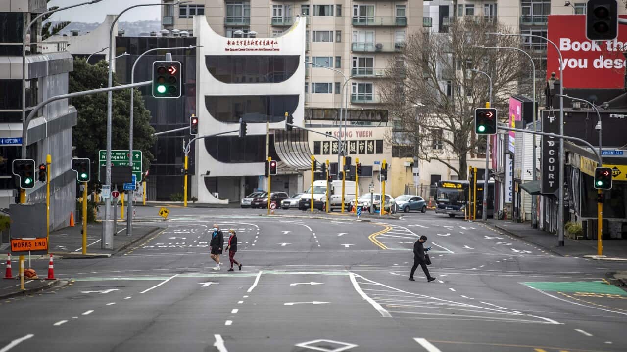 People cross nearly empty streets in the central business district of Auckland