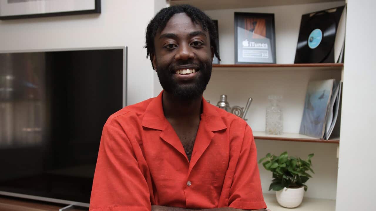 A man in a red shirt smiles.