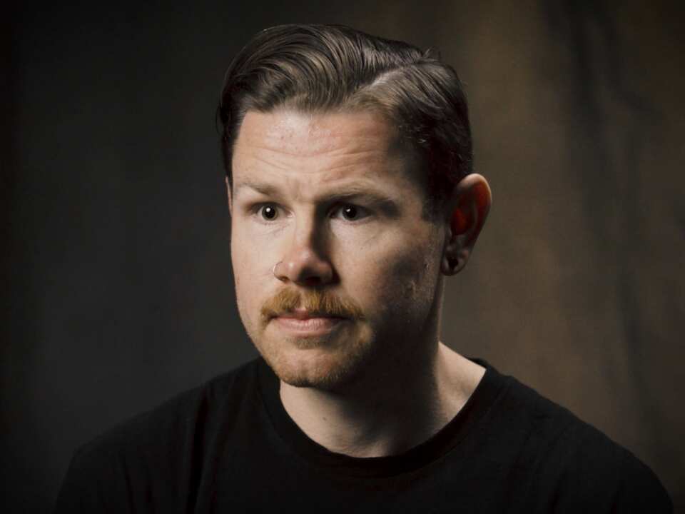 A man in a black shirt with a nose piercing.