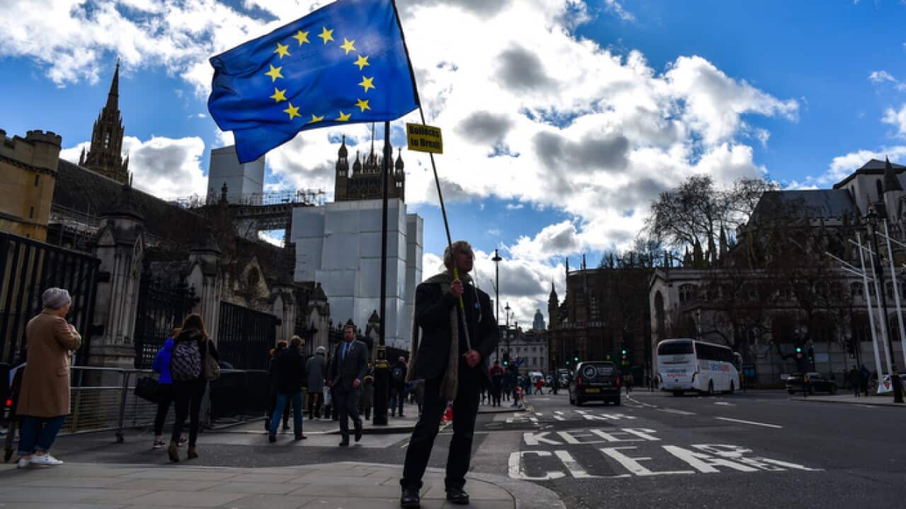 A man waves a EU flag outside the Houses of Parliament, London.