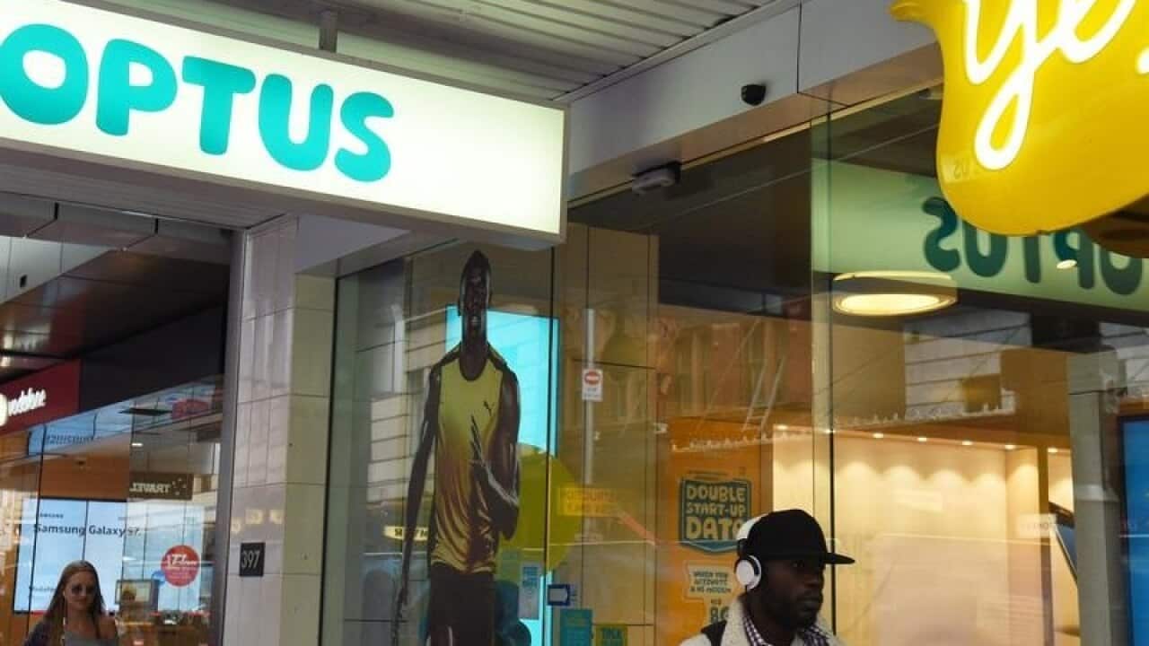 A man walks past an Optus store.