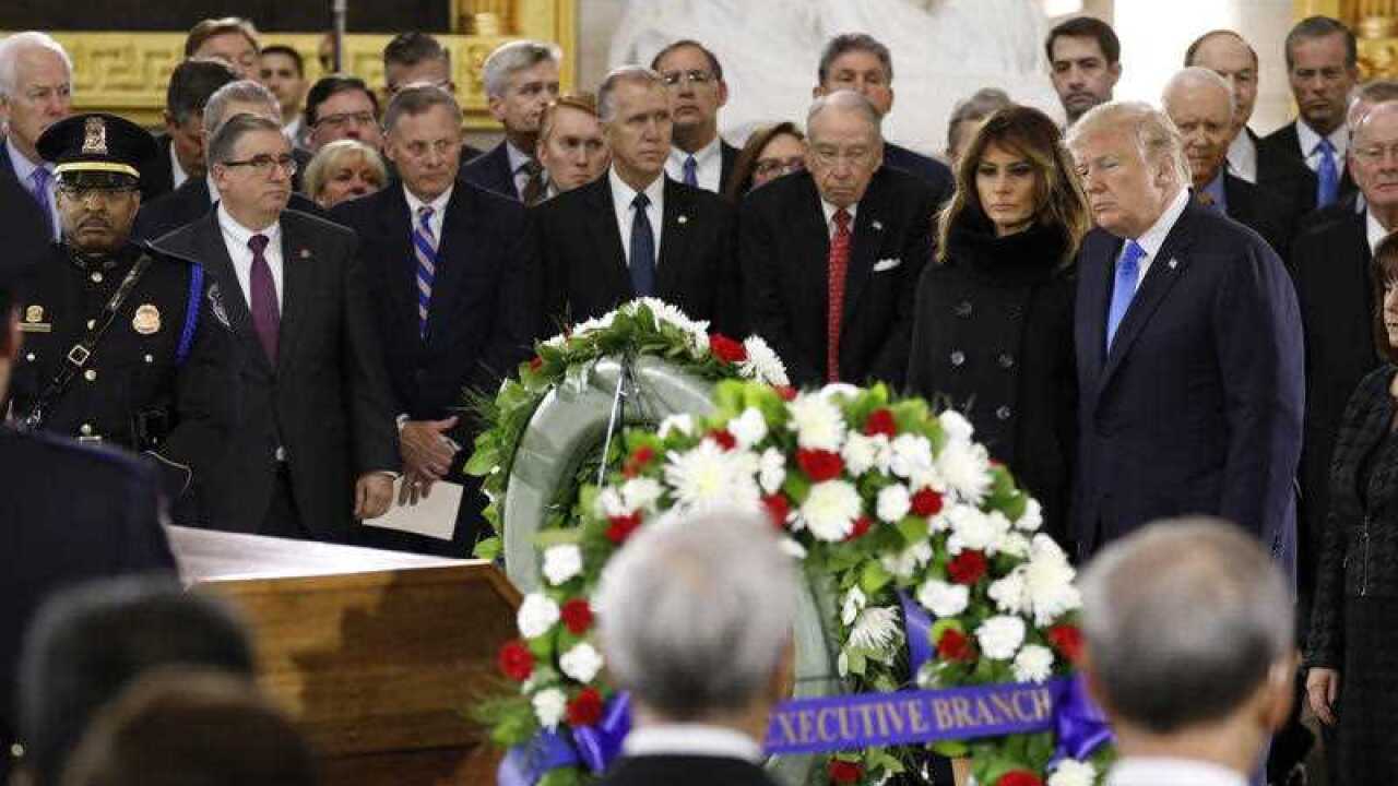 President Donald Trump and First Lady Melania Trump pay their respects at the casket together as the late evangelist Billy Graham lies in honour.