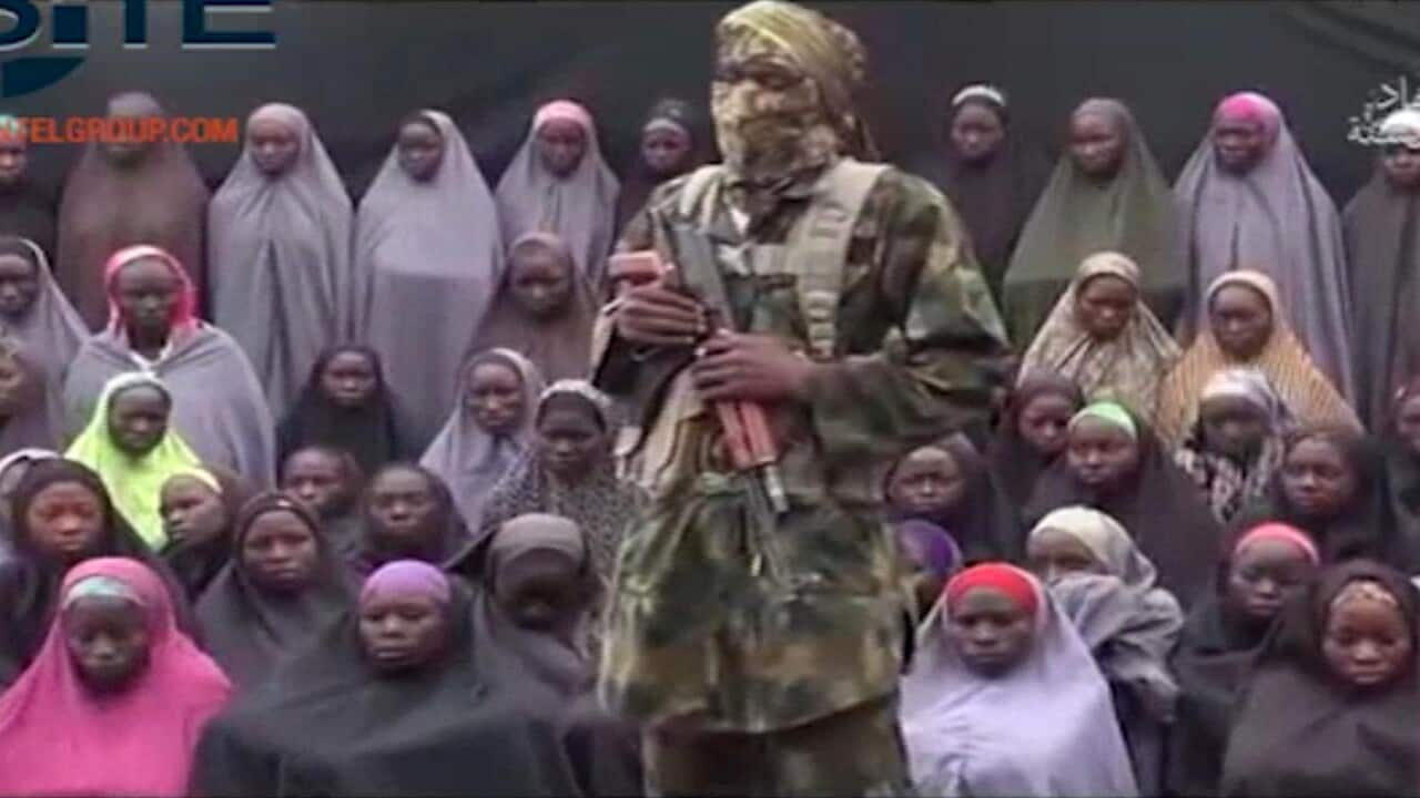 An alleged Boko Haram soldier standing in front of a group of girls alleged to be some of the 276 abducted Chibok schoolgirls held since April 2014