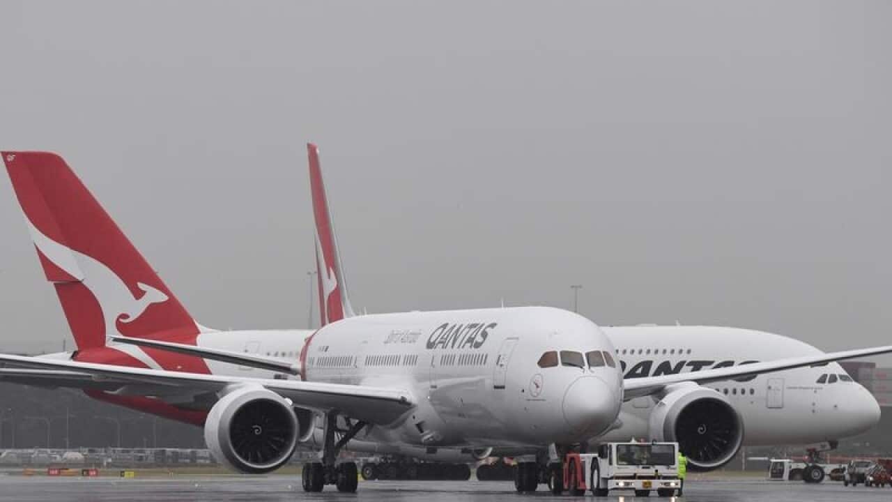 Qantas planes parked on wet airport tarmac on rainy day