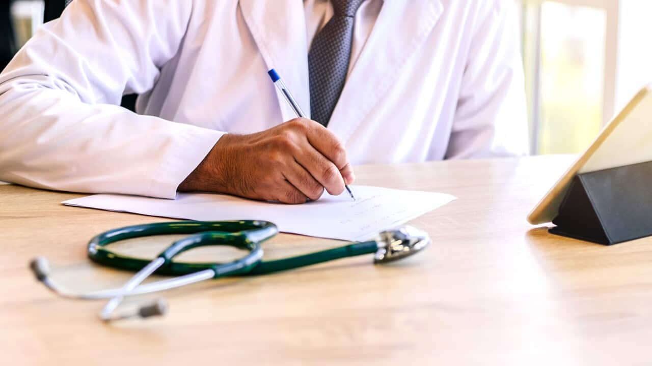 Indian doctor write medical prescription at his working place.