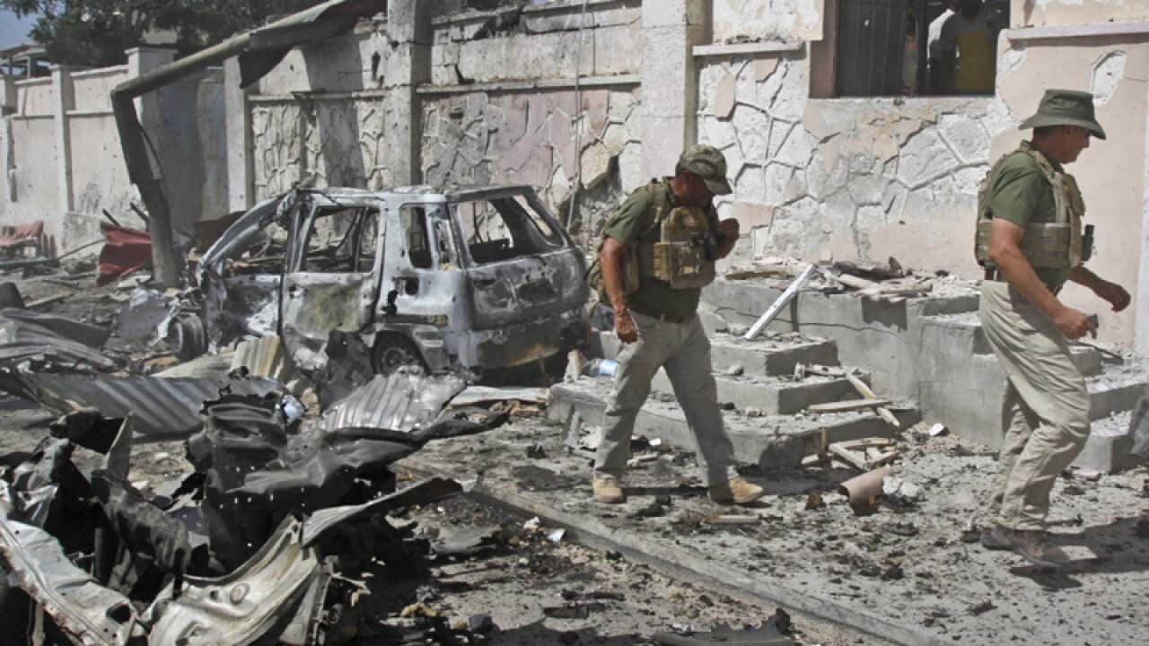 Security officers inspect wreckage at the scene of a suicide bomb
