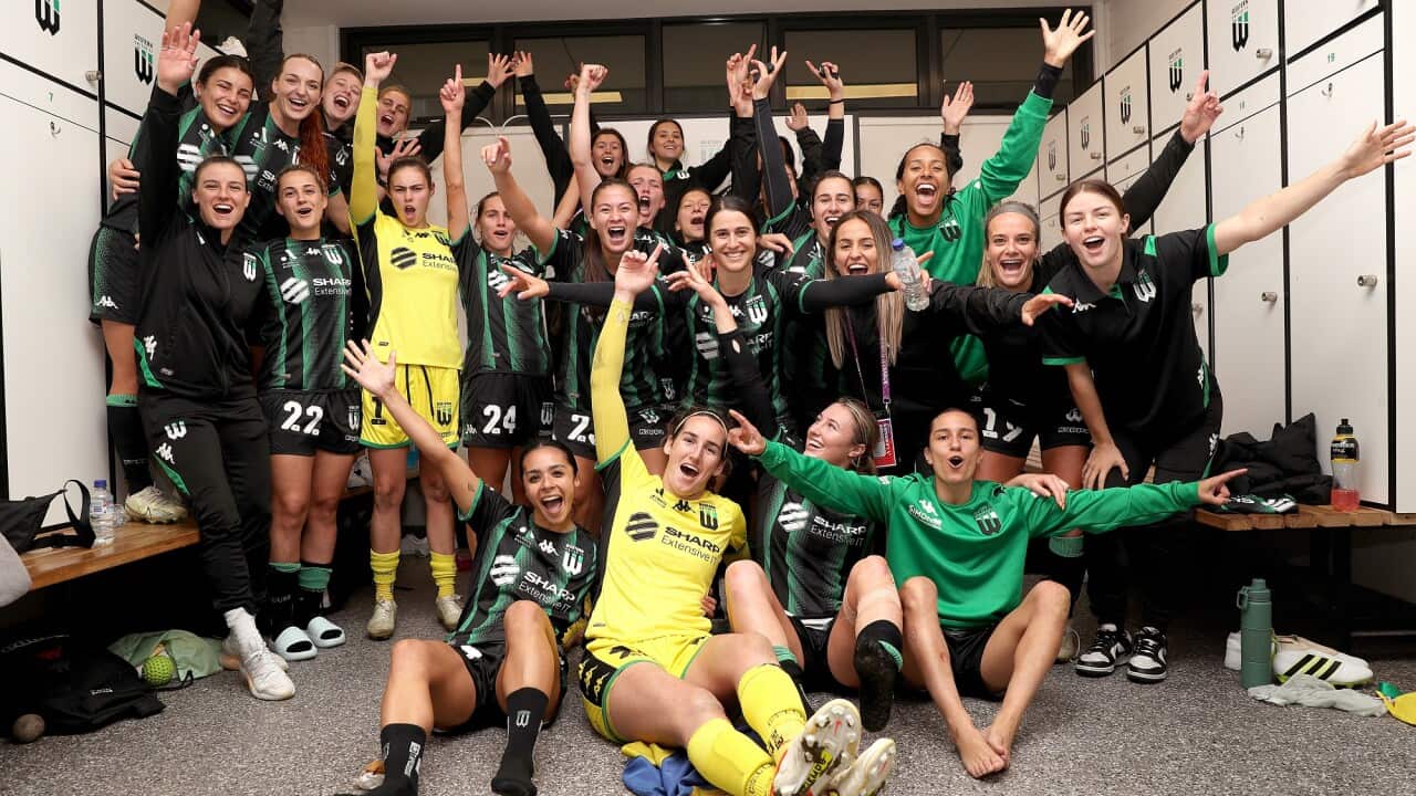 Members of the A-League Women's side Western United hold the arms in the air as part of a group photo.