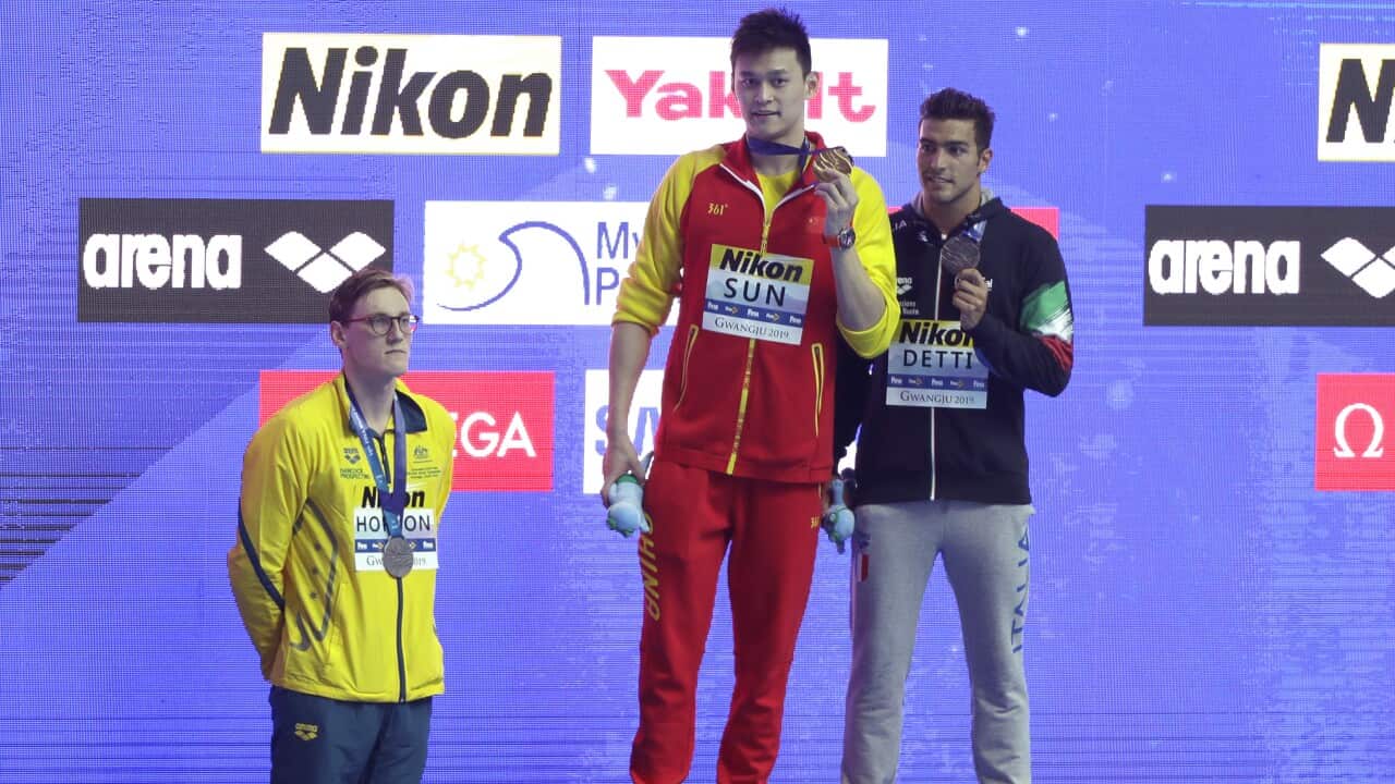 China's Sun Yang, centre, holds up his gold medal as silver medalist Australia's Mack Horton, left, stands away from the podium.