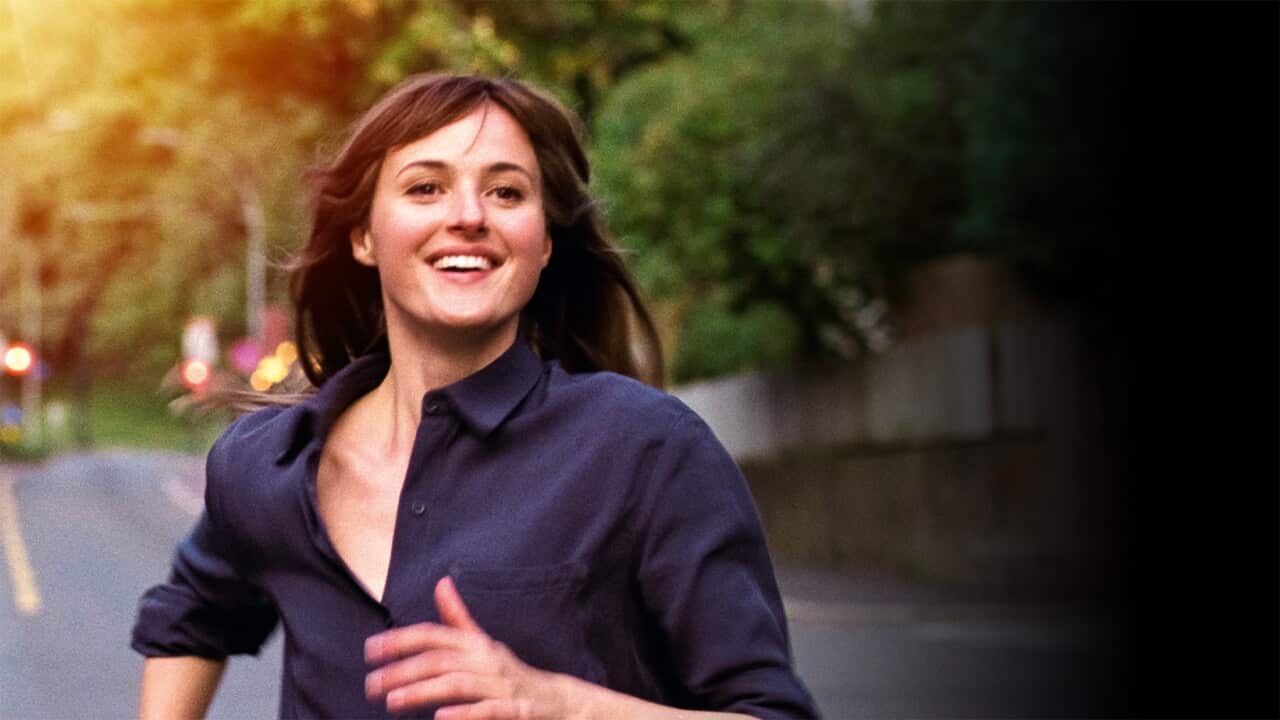 A woman runs down a road with a smile on her face.