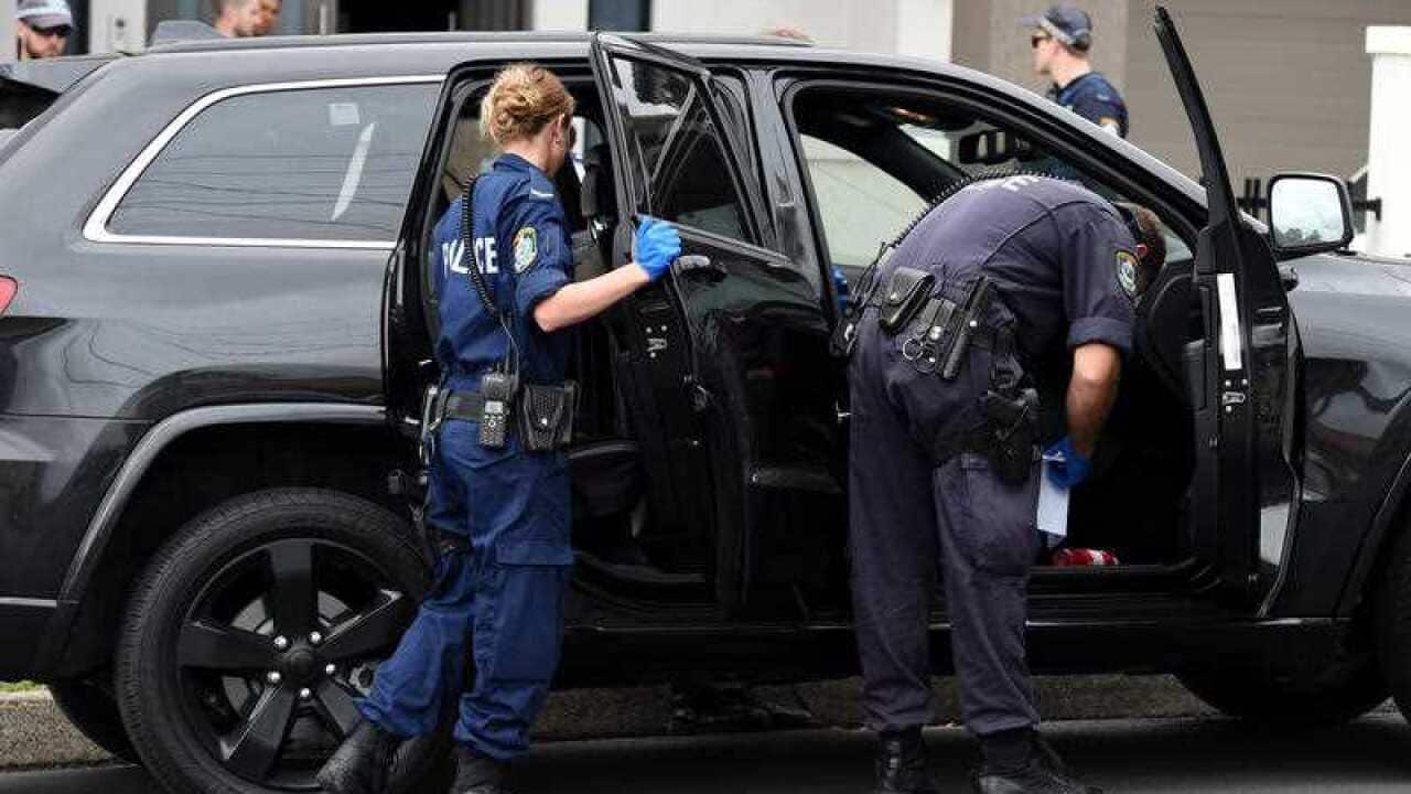 Police officers search a vehicle parked outside of a property in Sydney