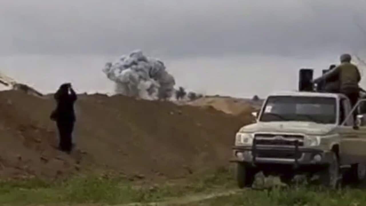 U.S.-backed Syrian Democratic Forces fighters looking at smoke rising.