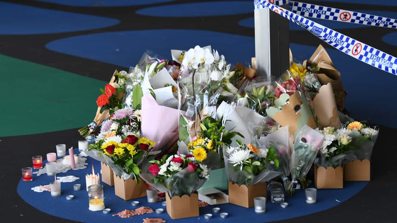 Bunches of flowers and candles near a crime scene.
