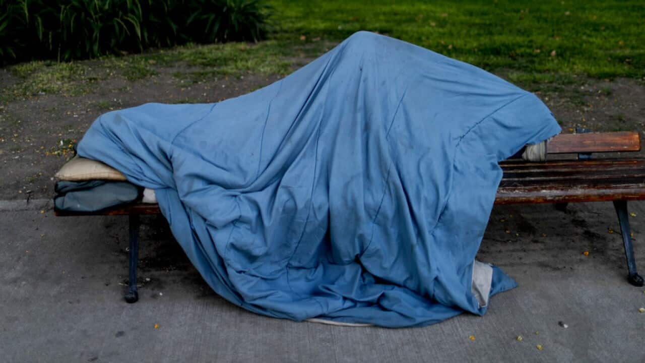 A homeless person asleep on a bench