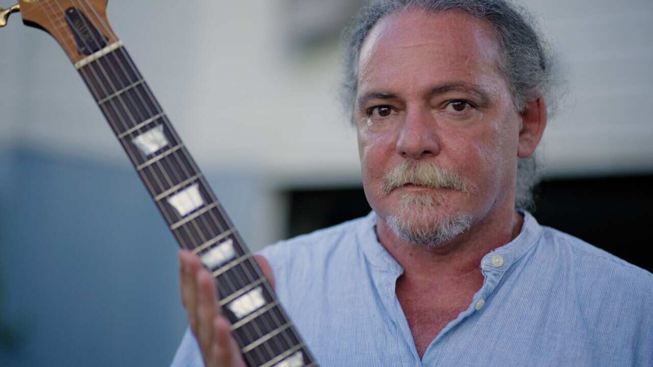 Gary Shallala-Hudson holding one of his homemade guitars