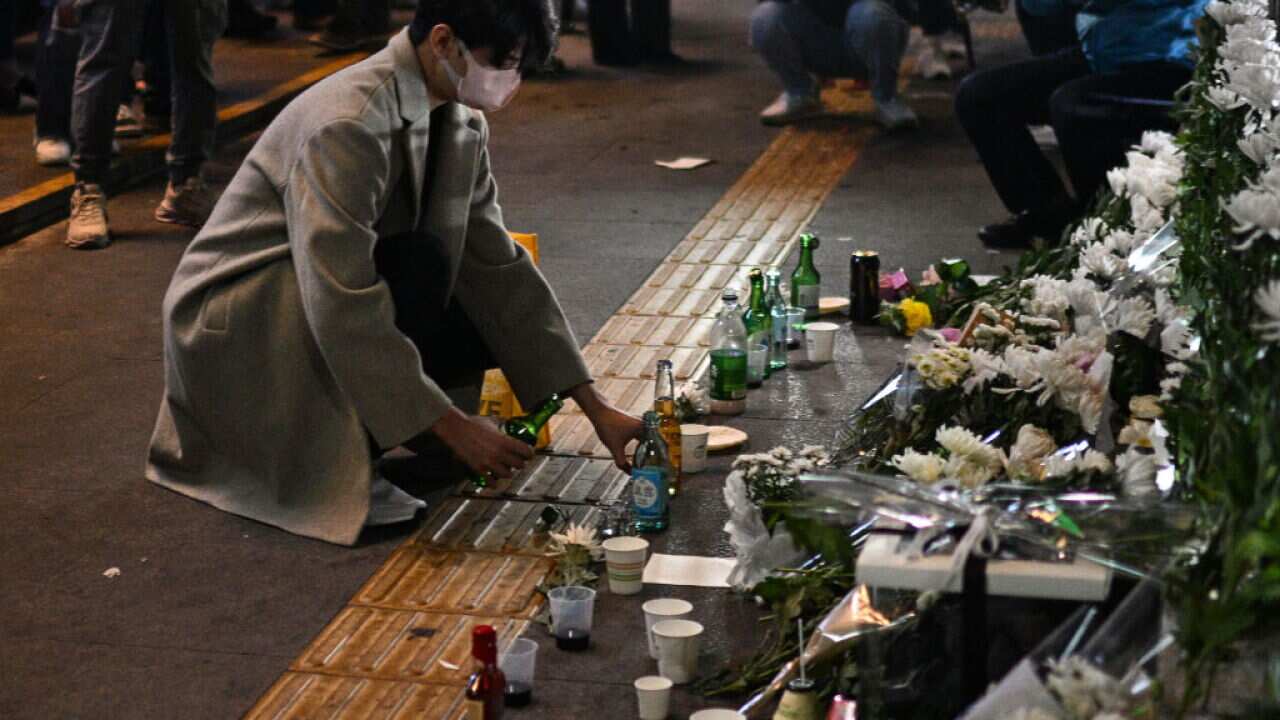 A man pours an alcoholic beverage in tribute to those who were killed in a Halloween stampede at a makeshift memorial outside the Itaewon subway station in the district of Itaewon in Seoul.