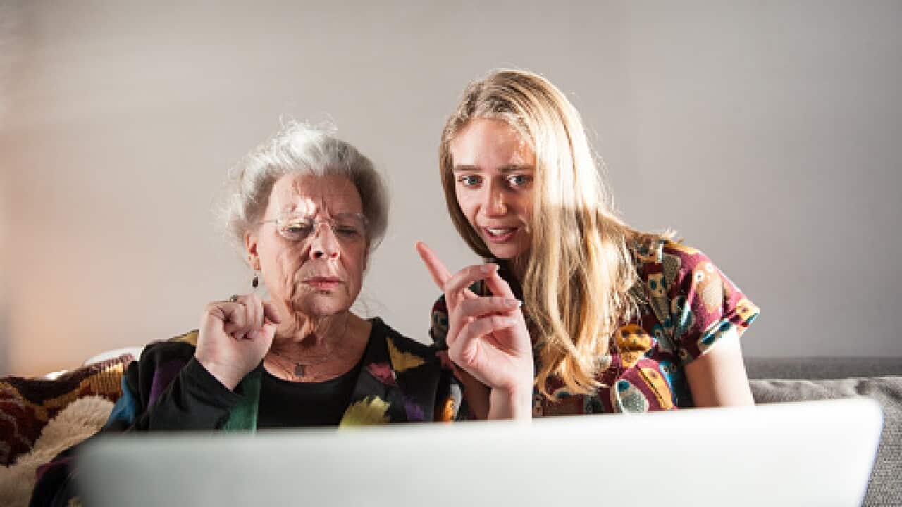 Young woman showing senior lady how to work laptop.