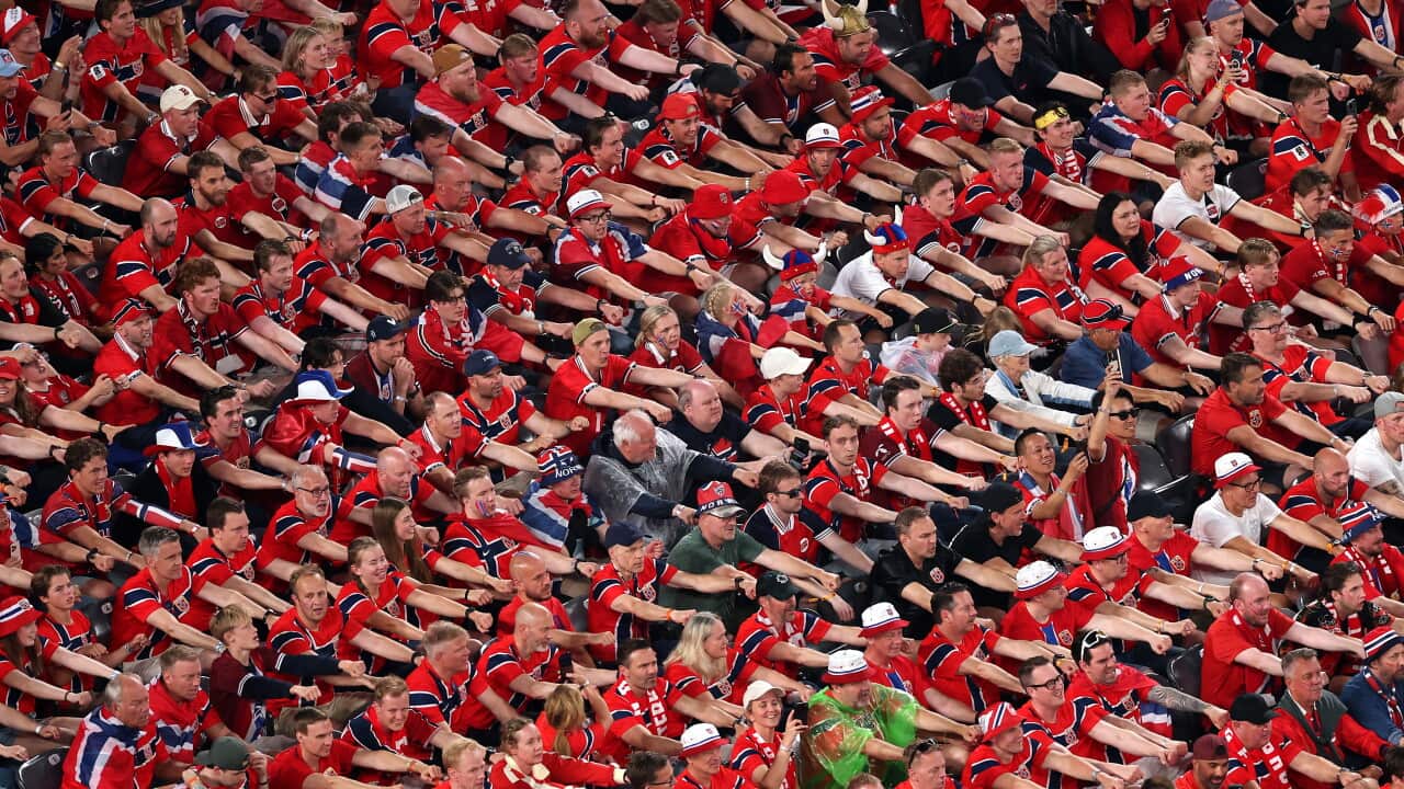 Norwegian football fans dressed in red performing the "Viking row" in a stadium