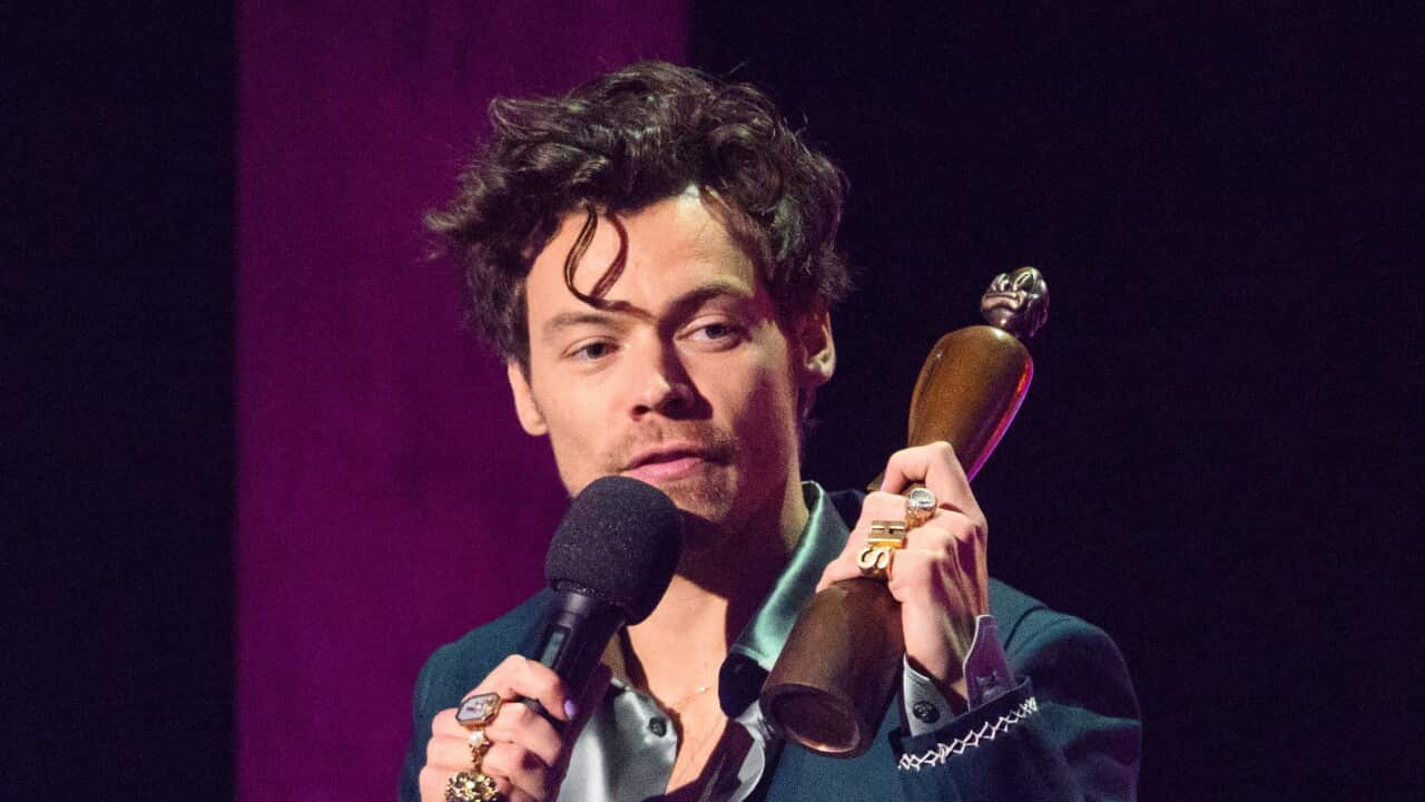 Harry STyles holds up a Brit Award statue